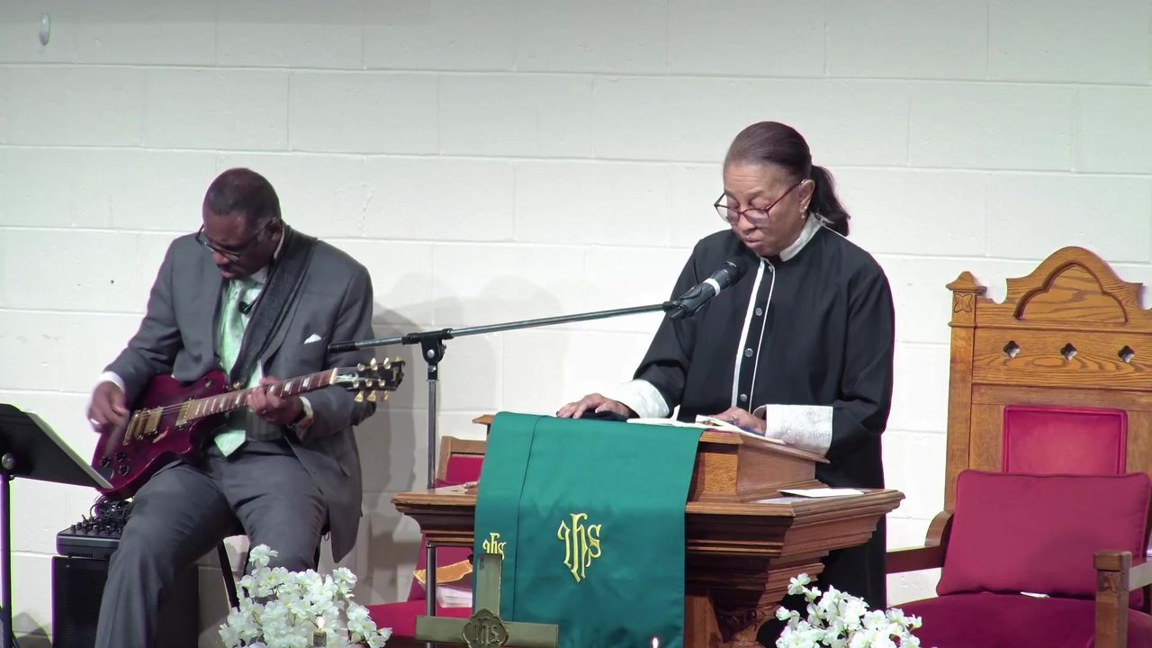 A guitarist plays softly as scripture is read from the pulpit