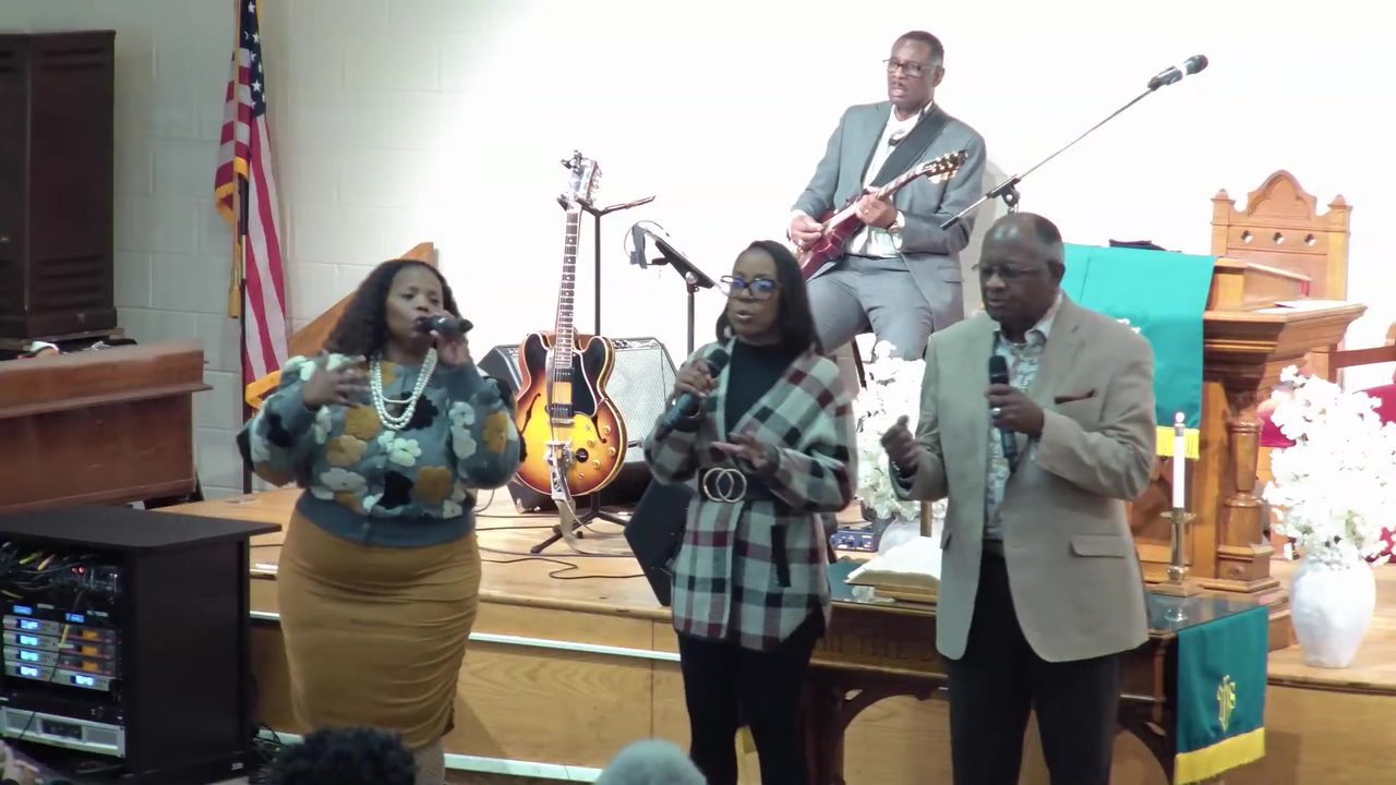 The praise team and guitarist lead music from the front of the church